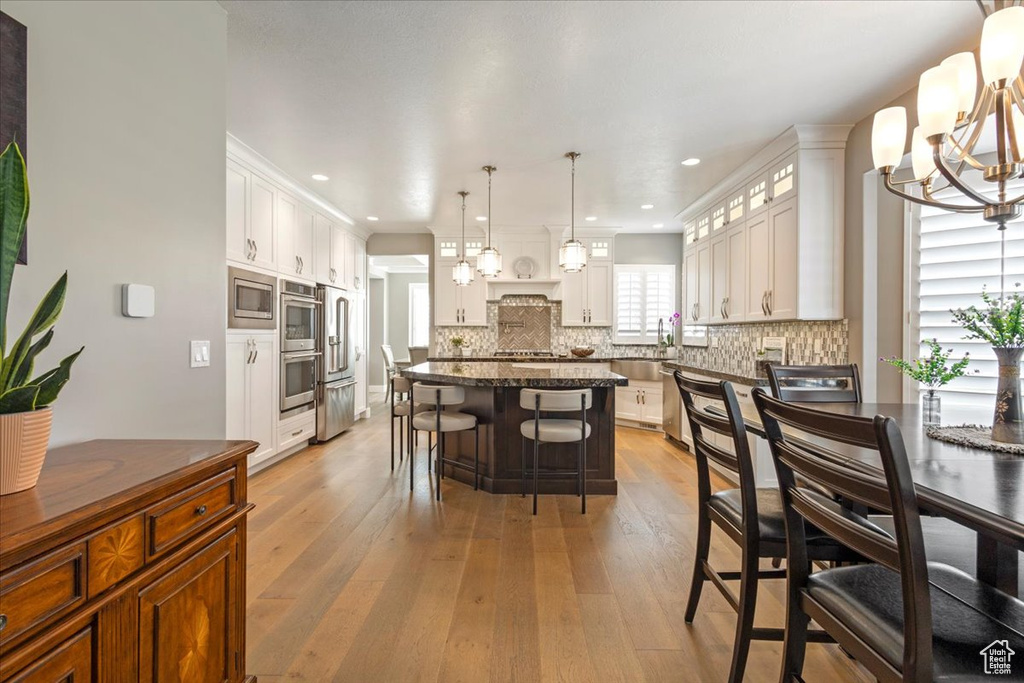 Kitchen featuring stainless steel appliances, a chandelier, light wood-style flooring, decorative backsplash, and recessed lighting