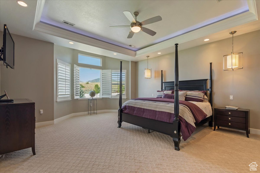 Bedroom with a raised ceiling, light carpet, baseboards, recessed lighting, and ceiling fan