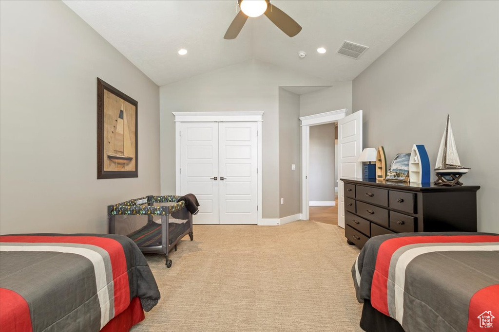 Bedroom featuring light colored carpet, vaulted ceiling, ceiling fan, a closet, and baseboards