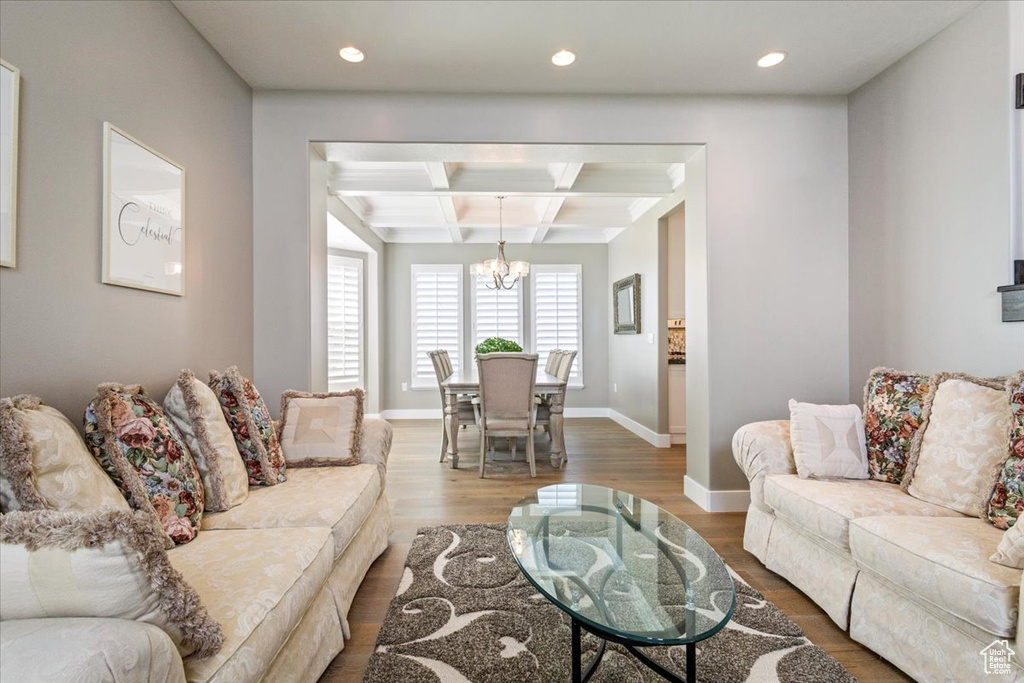 Living room featuring coffered ceiling, a chandelier, beam ceiling, wood finished floors, and recessed lighting