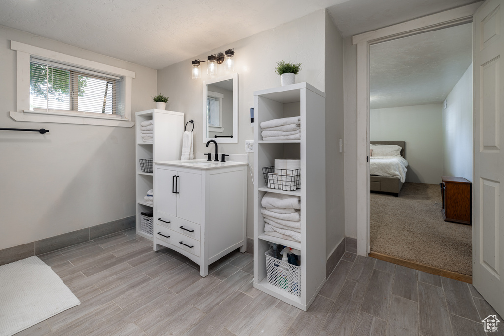 Full bath featuring vanity, wood finished floors, baseboards, and connected bathroom