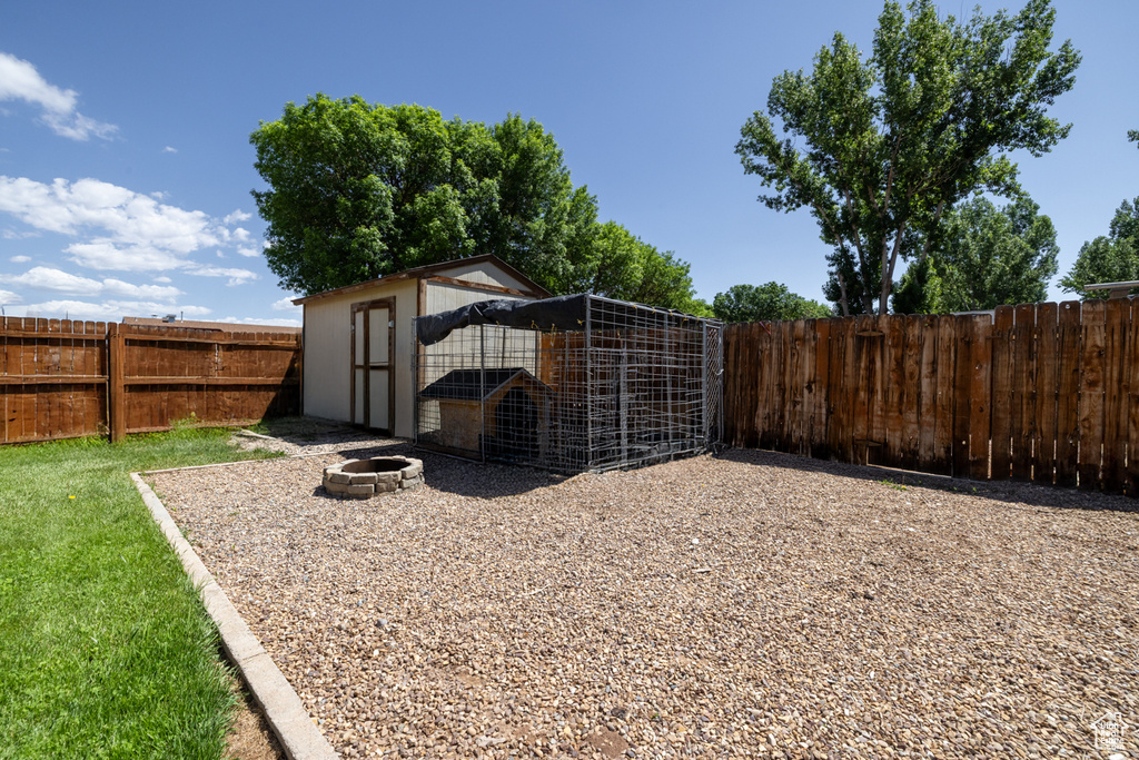 Fenced backyard with an outbuilding, exterior structure, and a fire pit