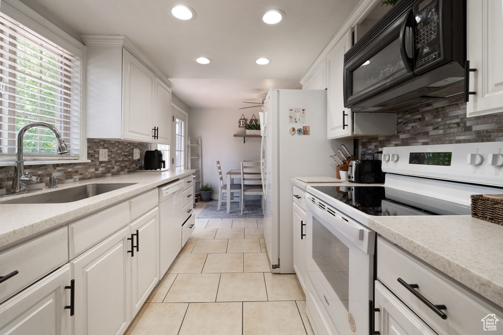 Kitchen with white appliances, a sink, recessed lighting, backsplash, and white cabinetry