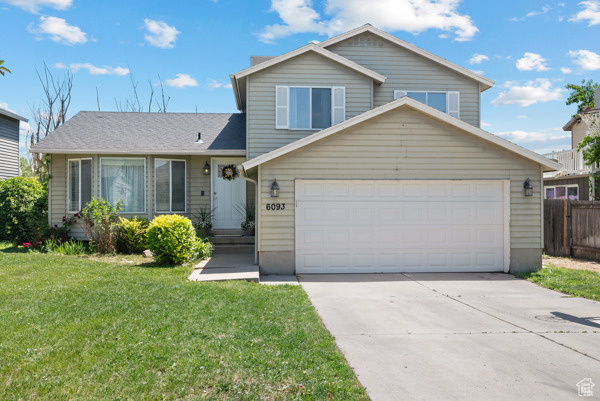 Tri-level home featuring concrete driveway and a garage