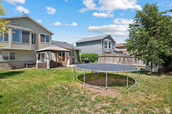 Rear view of property with a trampoline and a gazebo
