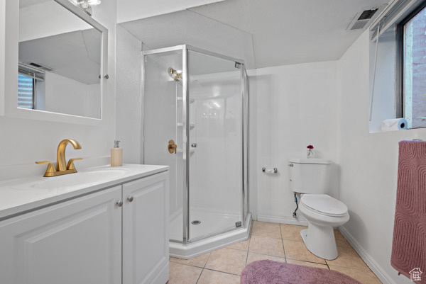Bathroom with vanity, a stall shower, toilet, and tile patterned flooring
