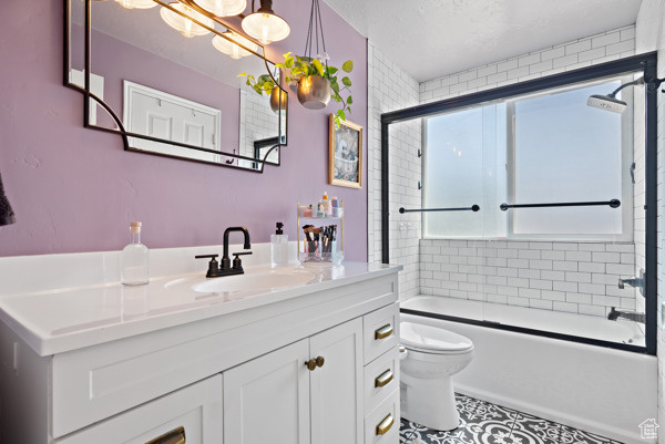 Bathroom with plenty of natural light, toilet, vanity, enclosed tub / shower combo, and a textured ceiling