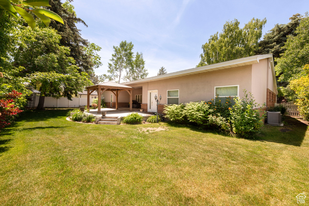 Back of house with a gazebo, stucco siding, central AC unit, and a patio
