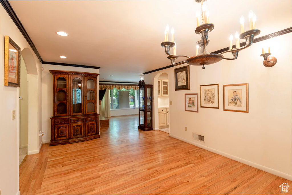 Hallway with arched walkways, light wood-type flooring, ornamental molding, recessed lighting, and baseboards