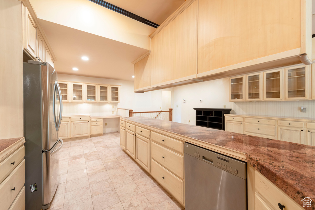 Kitchen featuring appliances with stainless steel finishes, glass insert cabinets, recessed lighting, ornamental molding, and light brown cabinets