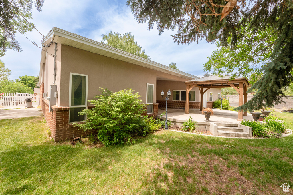 Back of property with a gazebo, a patio area, stucco siding, and brick siding
