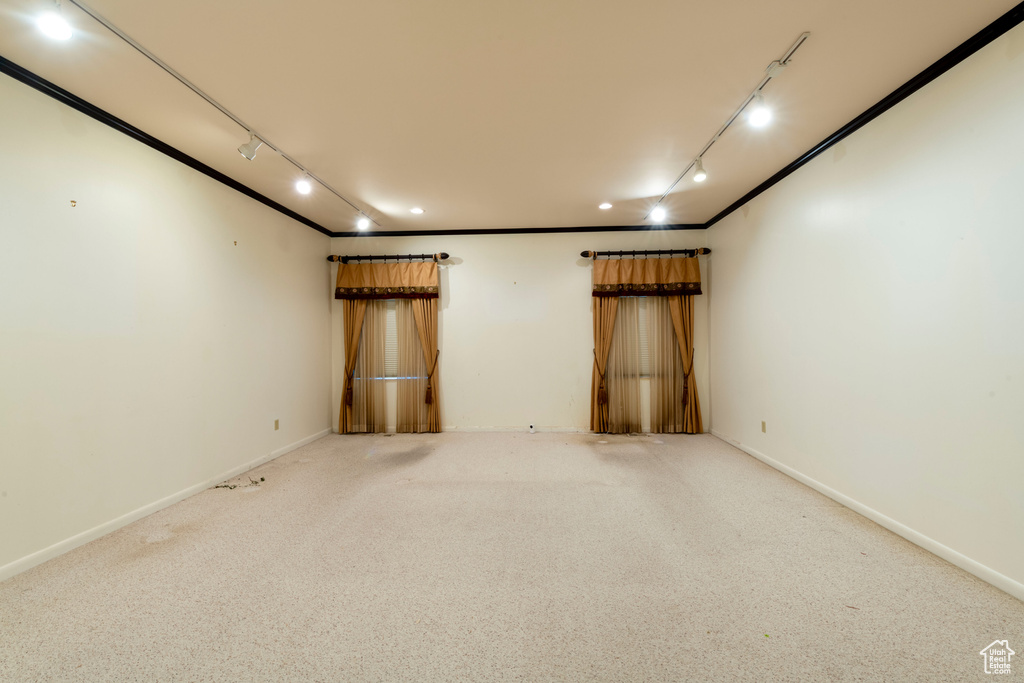Carpeted empty room featuring track lighting and baseboards