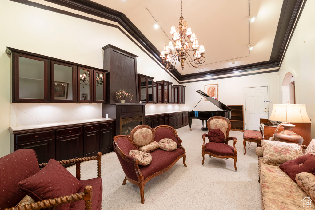 Living area with ornamental molding, carpet floors, vaulted ceiling, a chandelier, and track lighting