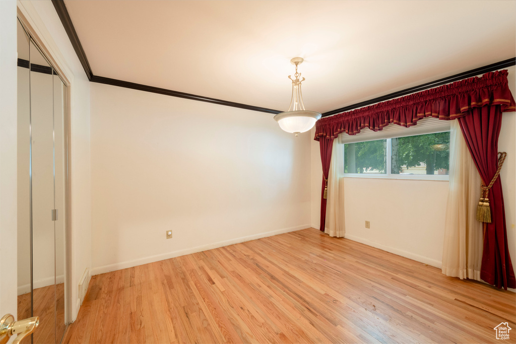 Unfurnished room with light wood-style flooring, crown molding, and baseboards