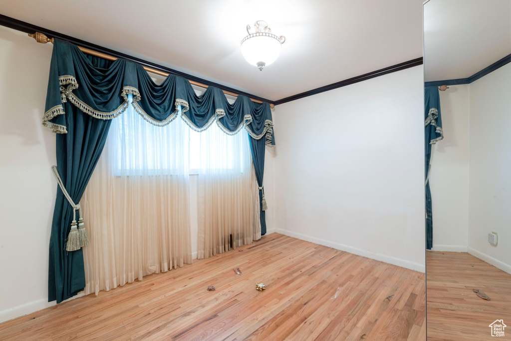 Unfurnished room featuring ornamental molding, baseboards, and wood finished floors