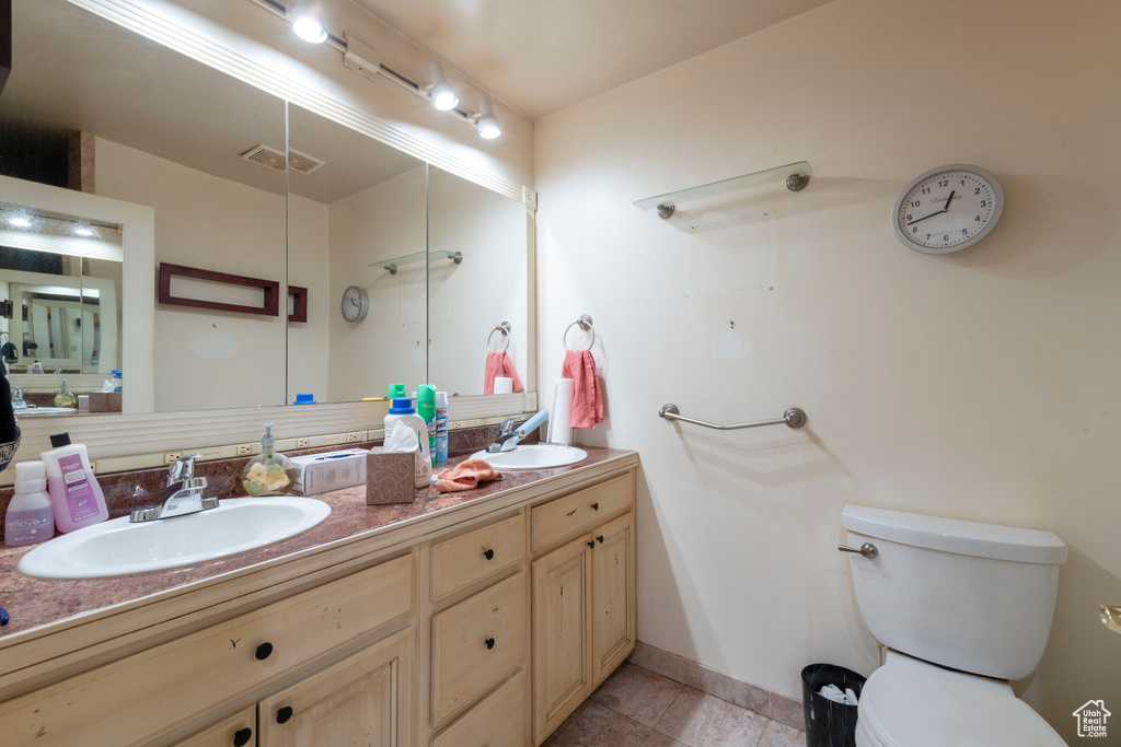 Full bath with double vanity, toilet, baseboards, and tile patterned floors