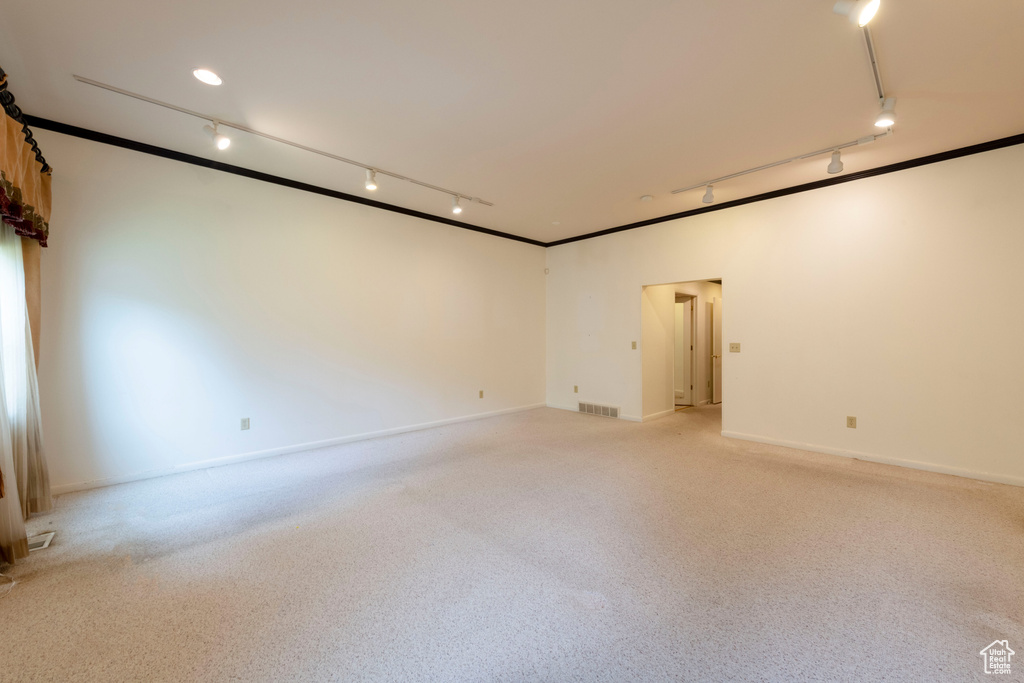 Empty room with rail lighting, light carpet, and baseboards