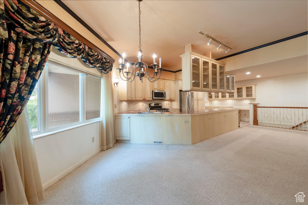 Kitchen with appliances with stainless steel finishes, a chandelier, glass insert cabinets, rail lighting, and light brown cabinetry
