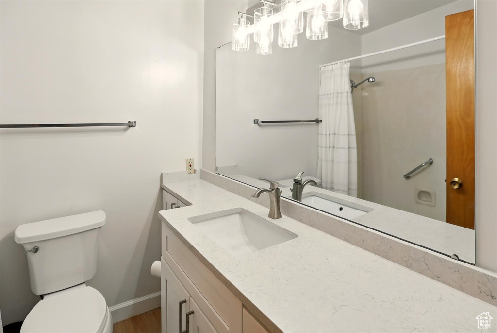 Full bathroom with toilet, vanity, baseboards, a chandelier, and a shower with curtain