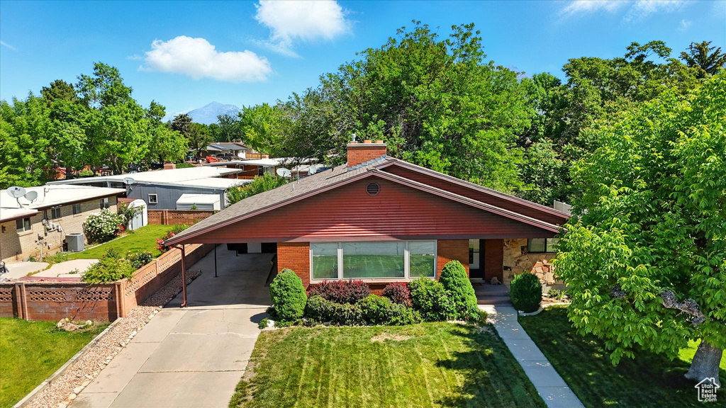 View of front of home featuring brick siding, an attached carport, driveway, a chimney, and a mountain view