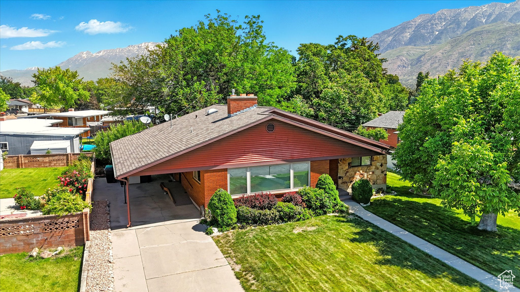View of front of house featuring a mountain view, driveway, an attached carport, brick siding, and a chimney