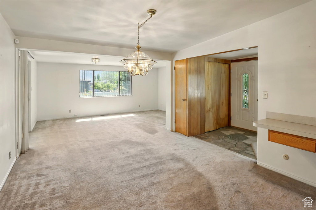 Unfurnished dining area with a chandelier, carpet floors, and baseboards