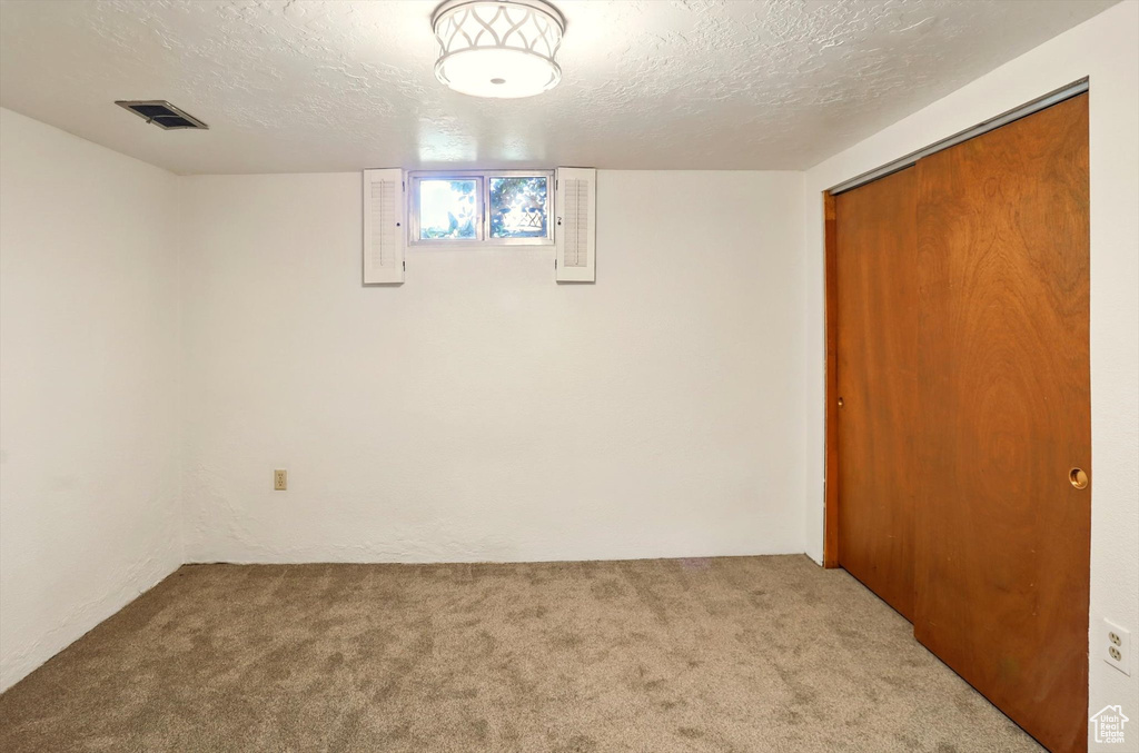 Below grade area featuring carpet floors and a textured ceiling