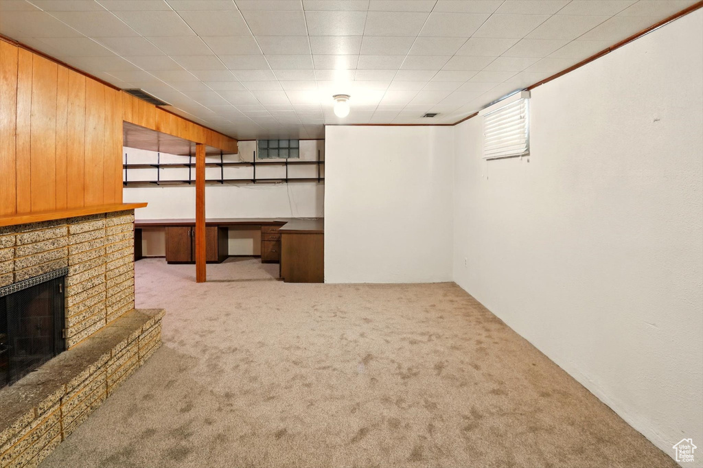 Basement featuring carpet flooring, a fireplace, and wood walls
