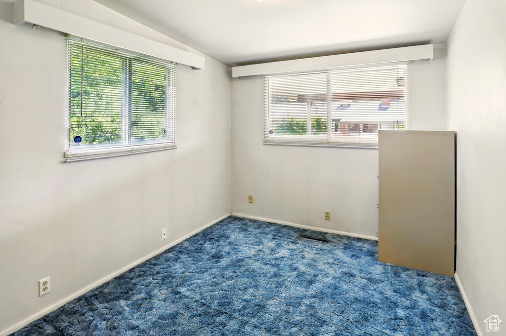 Carpeted empty room with baseboards and vaulted ceiling