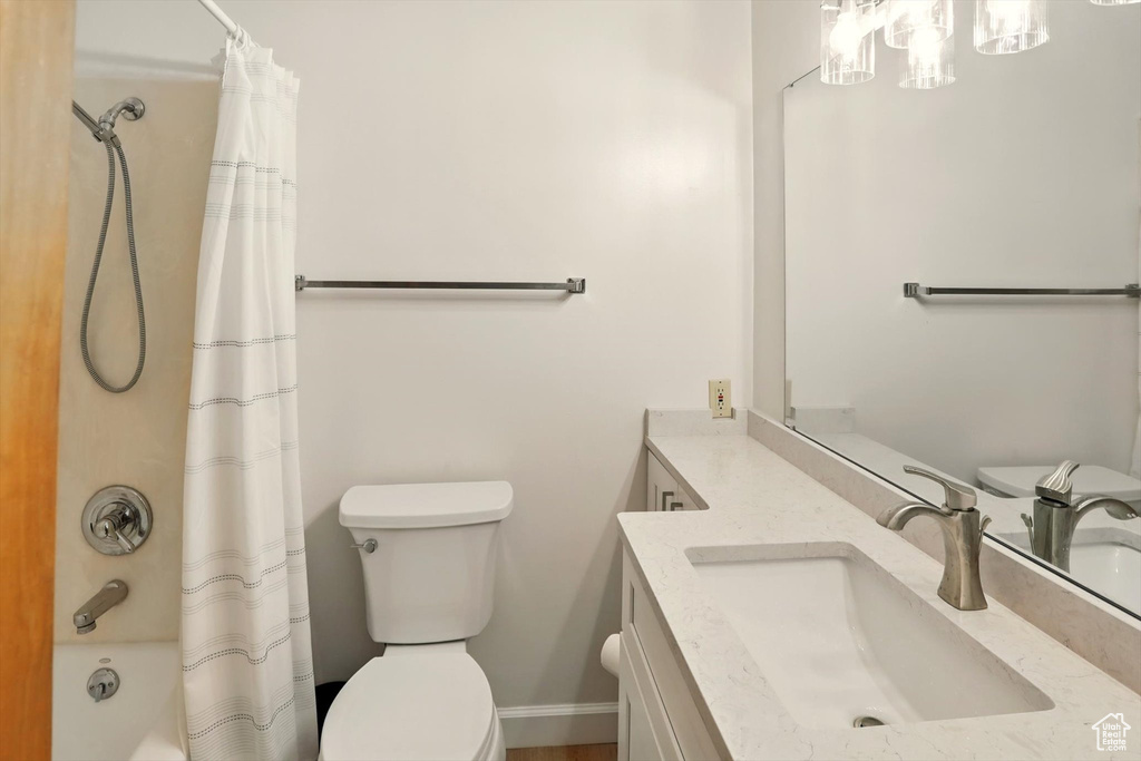 Bathroom featuring vanity, toilet, shower / bath combo with shower curtain, and baseboards