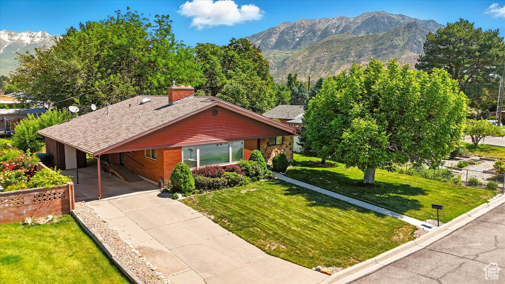 View of front of home featuring a mountain view, concrete driveway, an attached carport, brick siding, and a chimney