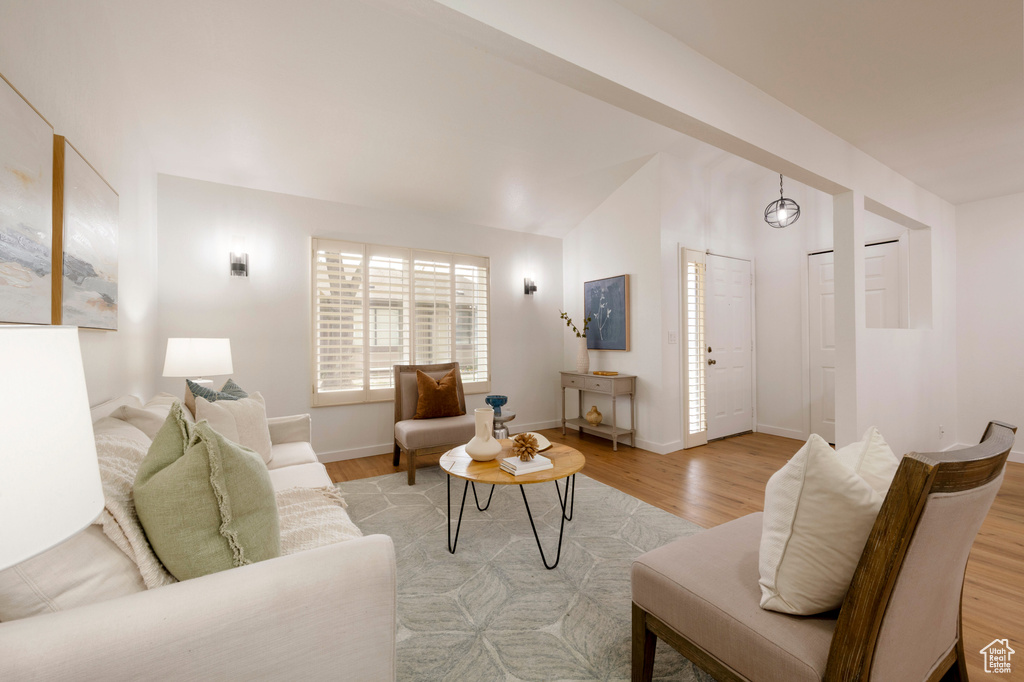 Living room featuring light wood finished floors, baseboards, and vaulted ceiling