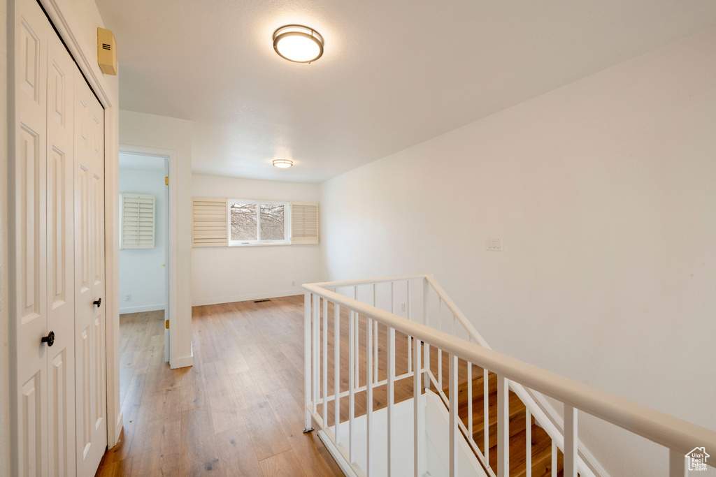 Hall featuring an upstairs landing, light wood-type flooring, and baseboards