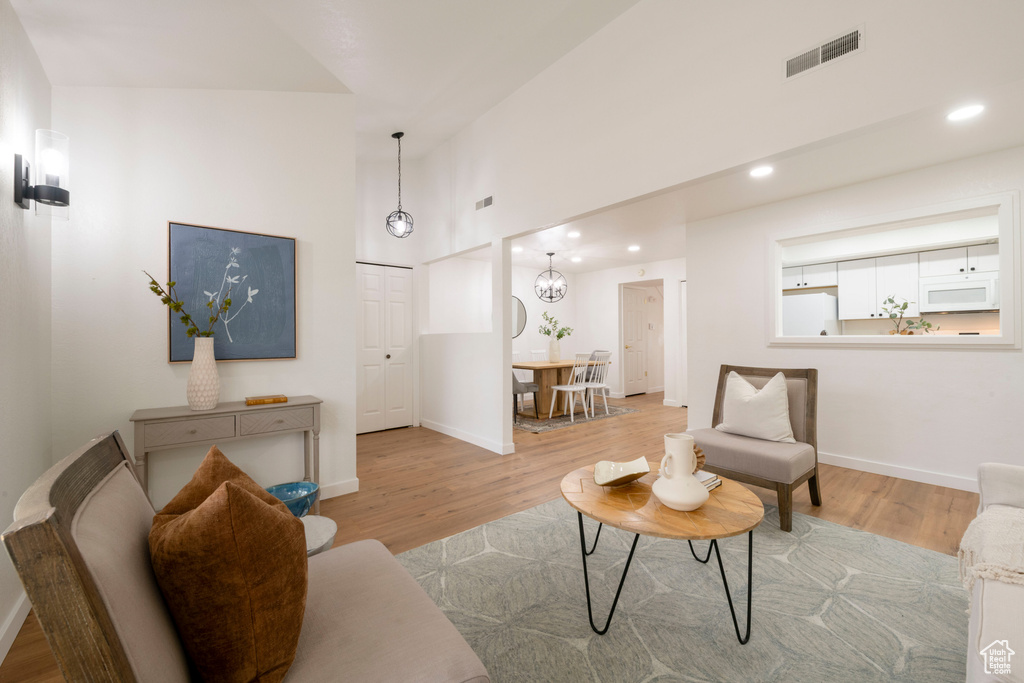 Living area with wood finished floors, recessed lighting, baseboards, and a high ceiling