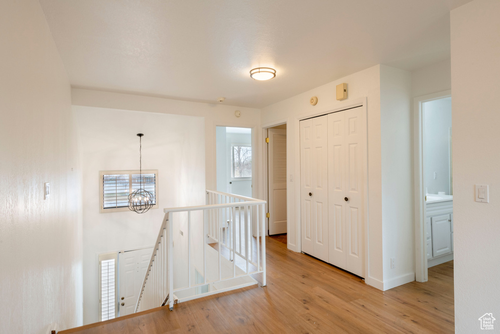 Hall featuring an upstairs landing, a chandelier, wood finished floors, and baseboards