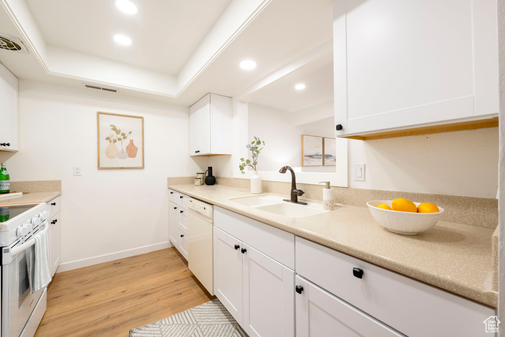 Kitchen featuring a sink, white appliances, recessed lighting, white cabinetry, and light wood-type flooring