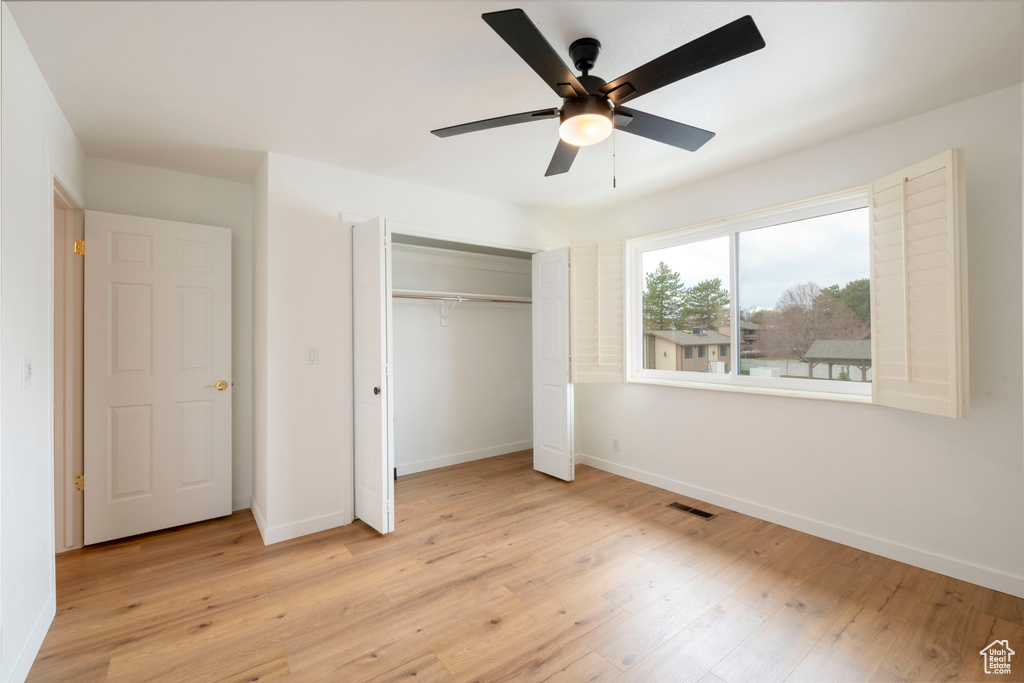 Unfurnished bedroom with light wood-style flooring, baseboards, a closet, and a ceiling fan