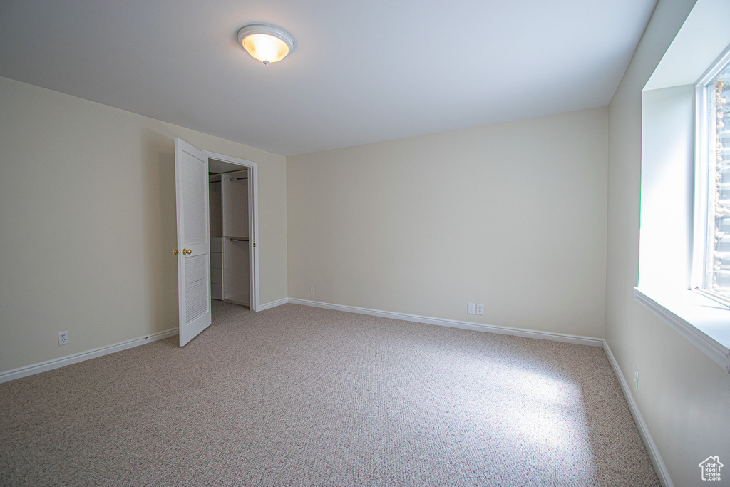 Unfurnished bedroom featuring multiple windows, baseboards, and a spacious closet