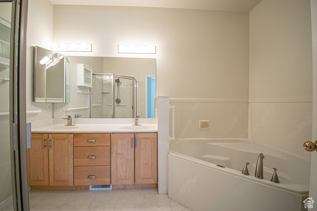 Full bath featuring a bath, a stall shower, double vanity, and marble finish flooring