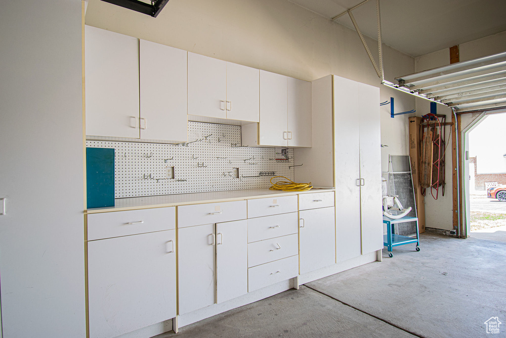 Kitchen featuring unfinished concrete flooring, white cabinets, light countertops, and plenty of natural light