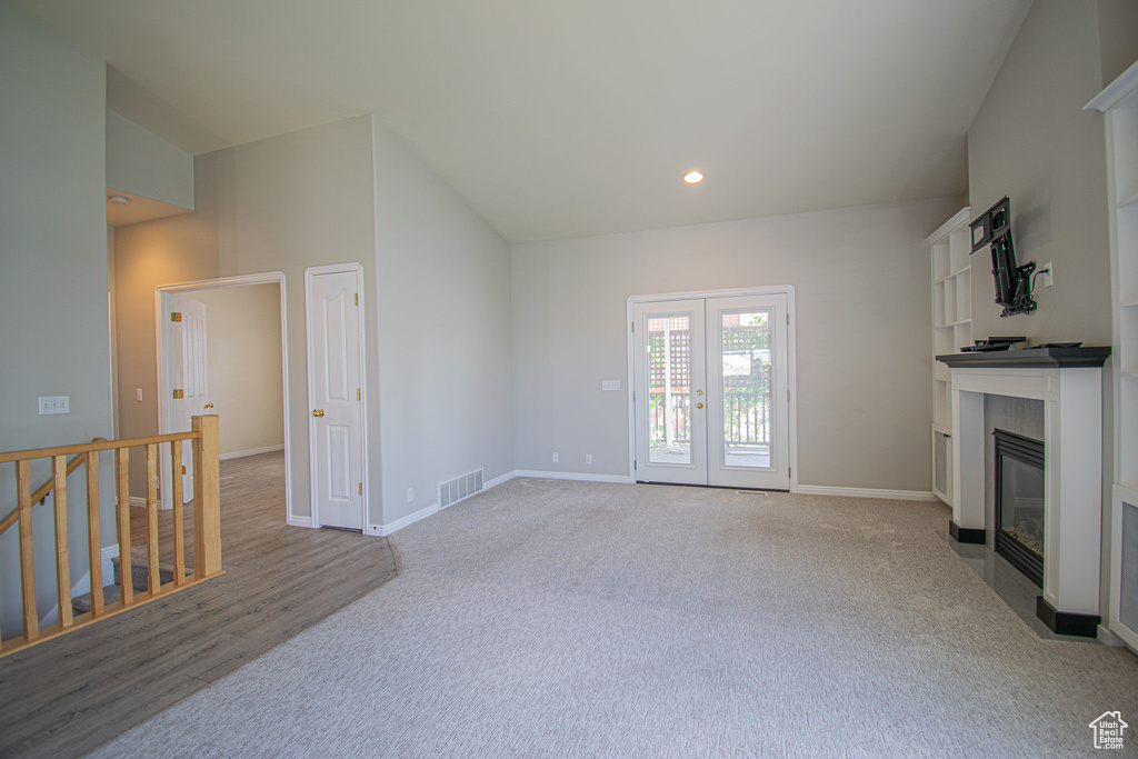 Unfurnished living room with carpet floors, french doors, baseboards, a tile fireplace, and recessed lighting