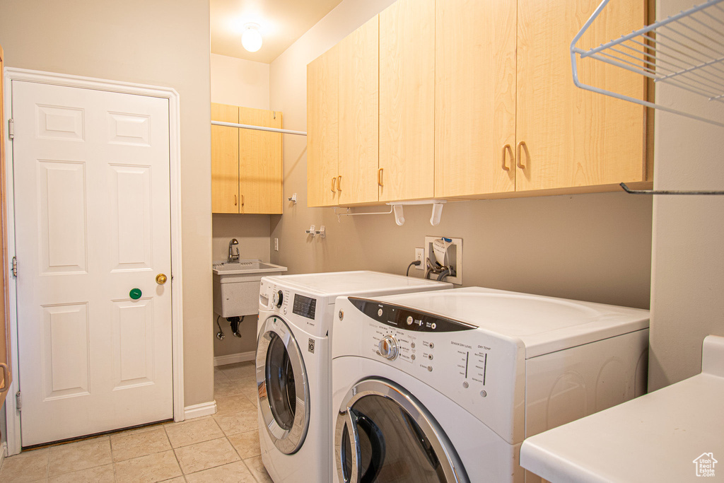 Laundry room with cabinet space, washing machine and dryer, light tile patterned floors, and baseboards