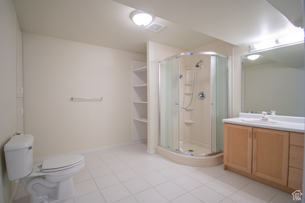 Bathroom featuring vanity, a shower stall, toilet, and tile patterned flooring