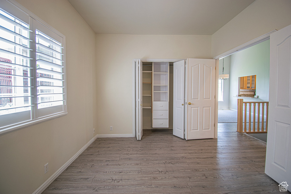 Unfurnished bedroom featuring wood finished floors, baseboards, and a closet