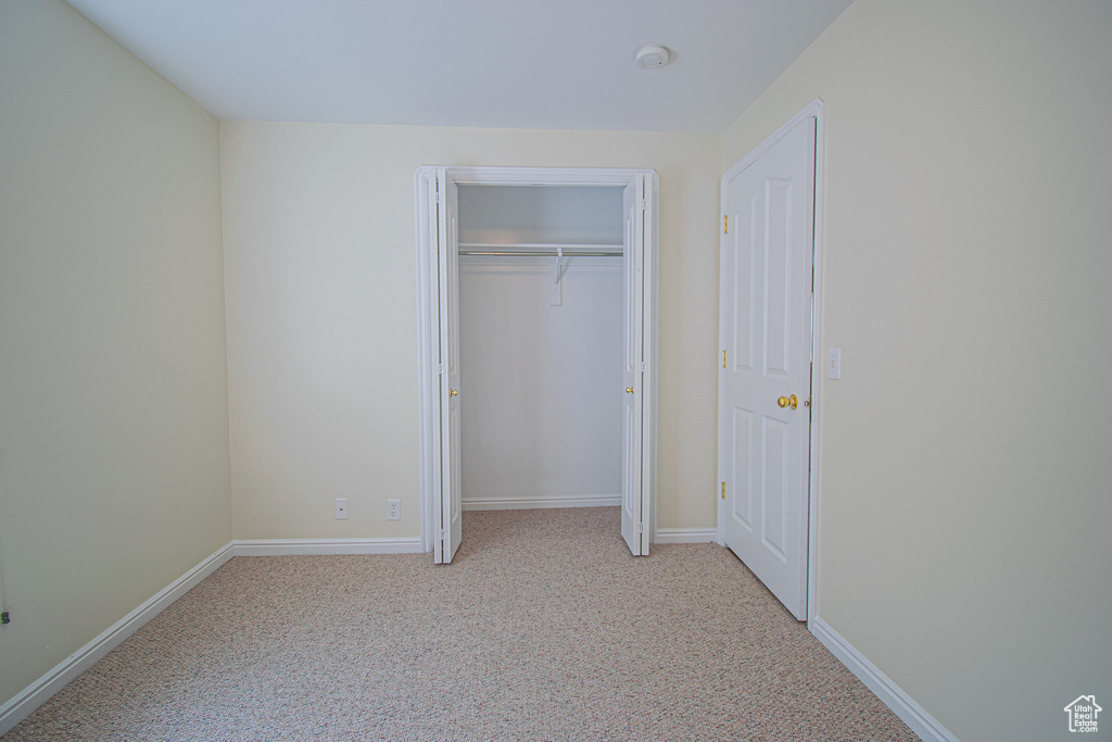 Unfurnished bedroom featuring carpet, baseboards, and a closet