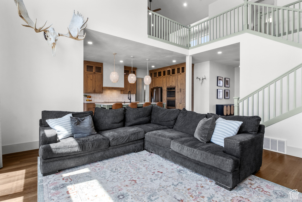 Living room with stairway, wood finished floors, a high ceiling, recessed lighting, and baseboards