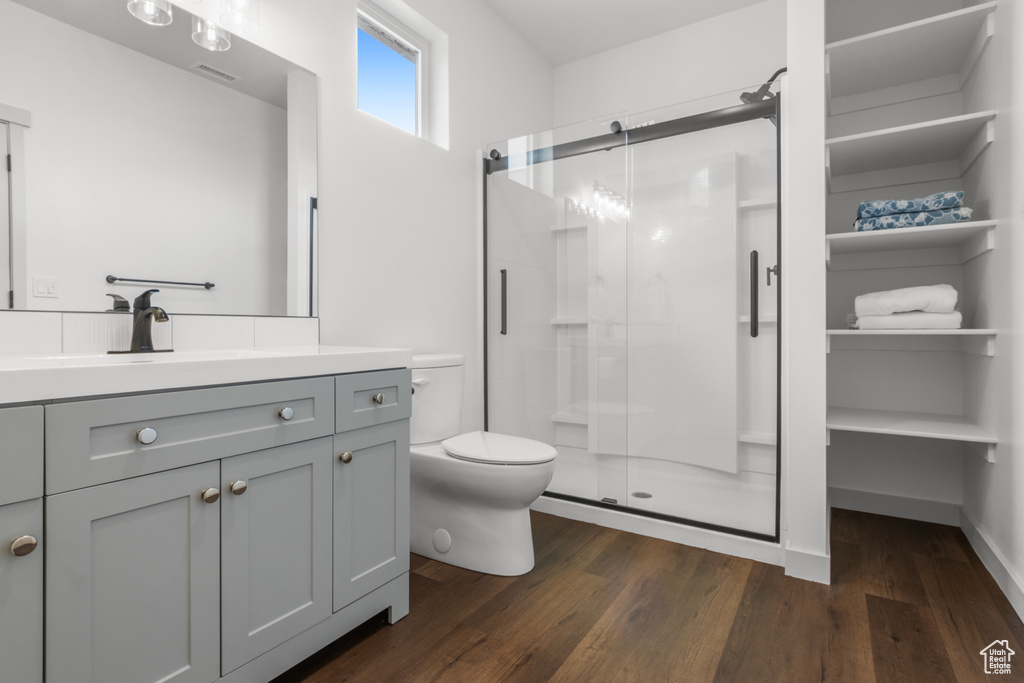 Bathroom featuring a stall shower, vanity, wood finished floors, and toilet
