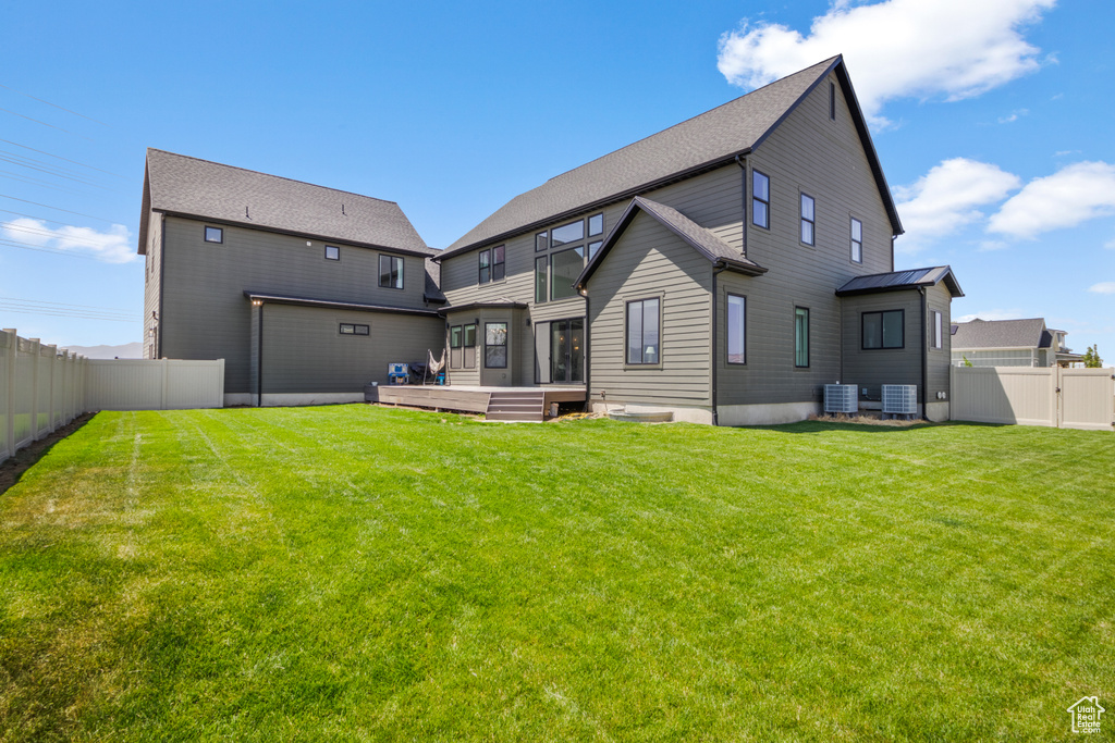 Back of property with a sunroom, central air condition unit, and a gate