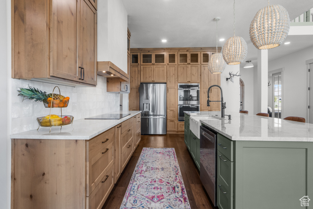 Kitchen with appliances with stainless steel finishes, a chandelier, a large island with sink, dark wood finished floors, and decorative backsplash