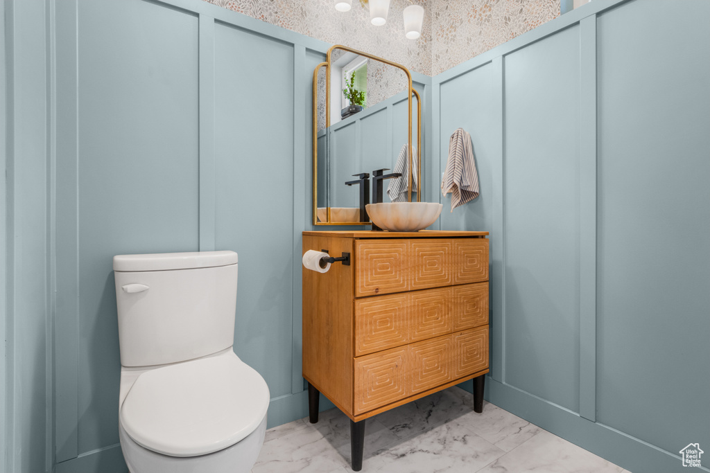Bathroom with marble look tile flooring, toilet, and vanity